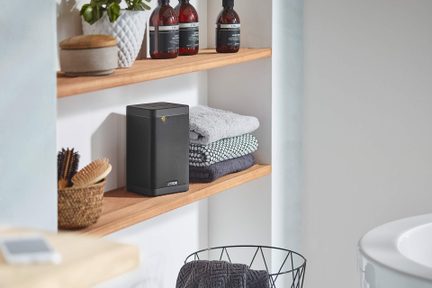 Boxă wireless Canton neagră, dreptunghiulară, pe raftul din baia cu prosoape împăturite