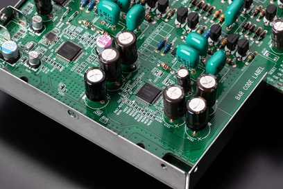 Zelený tištěný spoj s mnoha elektronickými součástkami, zejména stříbrnými elektrolytickými kondenzátory