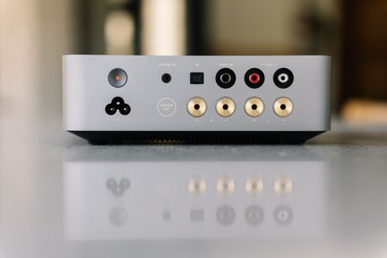 Harmaa kompakti hifi-vahvistin takaa kuvattuna, jossa on RCA-, koaksiaali- ja trigger-liitännät sekä kullatut kaiutinliittimet
