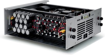 Stereo-Leistungsverstärker aus grauem Aluminium, Dreiviertelansicht von hinten links ohne Abdeckung, mit zwölf ausgerichteten schwarzen zylindrischen Kondensatoren, schwarzen Platinen mit roten und weißen Bauteilen, belüfteter Rückwand mit Drehklemmen und XLR-Anschlüssen
