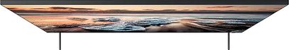 Samsung QE65Q900R TV set forfra, tændt skærm der viser et maritimt landskab ved solnedgang med varme og kontrastfyldte farver