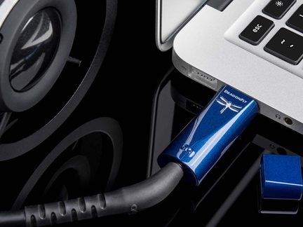 Adattatore audio USB in alluminio blu metallizzato con logo libellula, collegato a un computer portatile argentato, primo piano