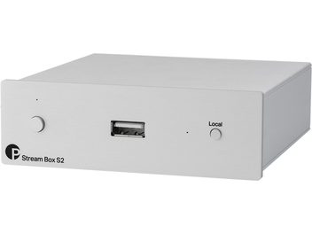 Lettore audio di rete Stream Box S2 in metallo chiaro, vista frontale angolata, pulsante circolare a sinistra, porta USB centrale, pulsante "Local" a destra