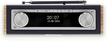 Radio da tavolo Roberts Rambler Uno blu navy, custodia rettangolare rivestita in similpelle blu navy con fianchi in legno chiaro, vista frontale che mostra lo schermo digitale centrale nero, due grandi manopole rotative argentate e antenna telescopica ripiegata sulla parte superiore.