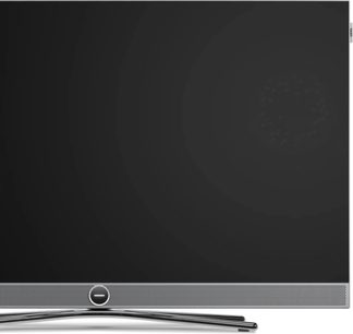 Loewe Vega 43-TV svart sett forfra, tynn sølvfarget ramme, perforert nedre grill og sentral forkrommet fot