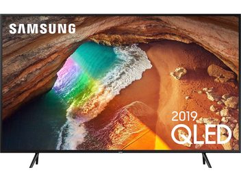 Televizor Samsung QE55Q60R zobrazující letecký pohled na pláž s pestrobarevnými vlnami a zlatými skalami