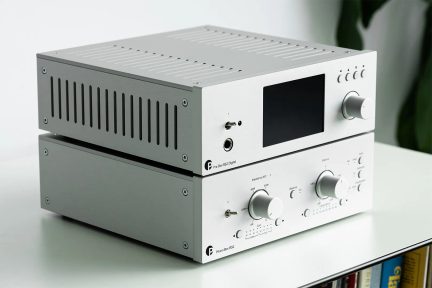 Pár strieborných hi-fi predzosilňovačov s veľkou čiernou obrazovkou, otočnými gombíkmi a slúchadlovým konektorom v trojštvrťovom pohľade