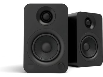 Zwart paar Kanto YU draadloze luidsprekers, mat houten behuizing, driekwart aanzicht met rechthoekige voorkant met afgeronde hoeken, bovenaan een tweeter, onderaan een woofer, een ronde knop en een LED onderaan