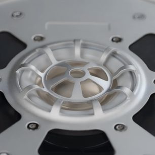 Close-up of the Final DX6000 headphone transducer, silver aluminum grille and chassis with exposed screws, top view