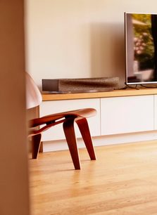 Altoparlante wireless connesso Naim Audio Mu-so 2nd Gen in legno chiaro, vista laterale, posizionato su un mobile in legno chiaro