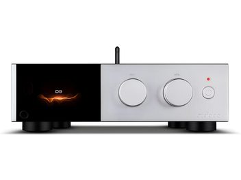 Audiolab D9 strieborný audio prevodník, pohľad spredu, hliníkové brúsené telo s ľavým panelom z čierneho skla so sýto oranžovým podsvietením, dva veľké okrúhle ovládacie gombíky na výber a hlasitosť, malý tlačidlový vypínač s červenou LED a viditeľná zvislá zadná anténa