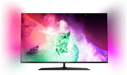 Philips 55PUS7909 TV-skærm, der viser en skiløber, der springer i en sky af farvet puddersnee mod en stjernebestrøet himmel