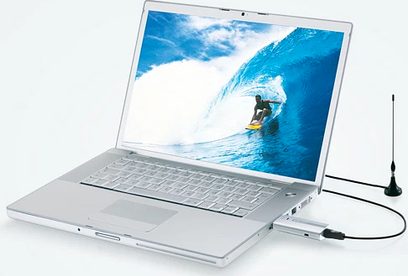 Åben sølvfarvet bærbar computer, der viser et billede af en surfer på en bølge, tilsluttet en sort USB-nøgle