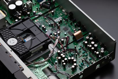 Vista interior de um leitor de CD Marantz CD6007 prateado dourado mostrando os componentes eletrônicos em uma placa de circuito impresso verde