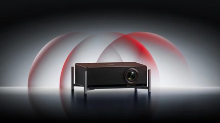 Czarny projektor kina domowego IMAX Enhanced na metalowym uchwycie, z czerwonym świetlistym halo w tle