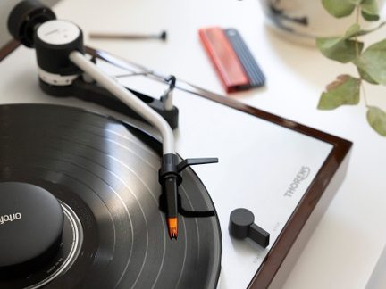Vinilo grotuvas, nuskaitanti galvutė su adatėle, vinilo plokštelė, trintukas, pieštukas, trintukas ir lapas ant balto paviršiaus