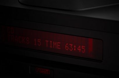 Червен цифров дисплей, показващ "15 TIME 63:45" на черно електронно устройство, засенчен отблизо отпред в тъмното