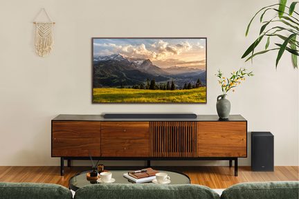 TV, der viser et bjerglandskab ved solnedgang, placeret på et TV-møbel af træ i en stue