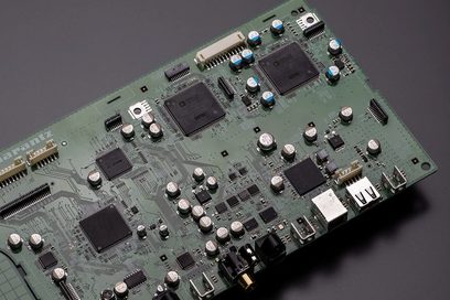 Grønt printplade med mange elektroniske komponenter såsom chips, kondensatorer og stik, tæt på visning