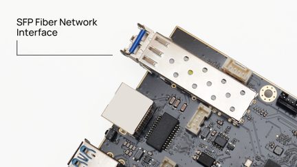 Electronic board viewed at an angle, perforated metal SFP connector, black rectangular components, white connectors, printed circuits