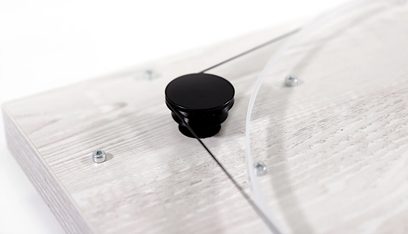 Glanzende zwarte knop op licht houten oppervlak met zichtbare schroeven, close-up bovenaanzicht