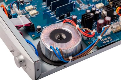 Nuprime PRA-9X sølvfarvet stereo-forforstærker, nærbillede af toroidaltransformatoren og de interne elektroniske kredsløb