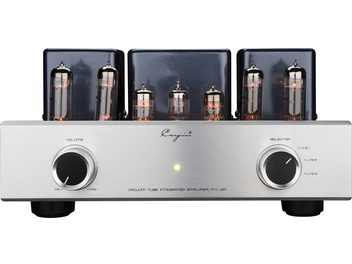 Priekinis vaizdas į Cayin MT-12N stereo lempinį integruotą stiprintuvą: sidabrinė šlifuoto aliuminio priekinė panelė su dviem juodais metaliniais apvadais mygtukais, centriniu žaliu LED indikatoriumi ir šešiomis išrikiuotomis šviečiančiomis stiklinėmis lempomis priešais tris juodus metalinius transformatorių gaubtus.