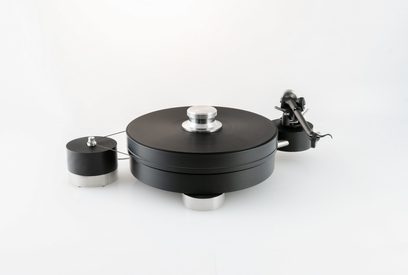 Platina de vinilo hi-fi Transrotor Max Nero RB330 negra de metal, vista en tres cuartos desde arriba, mostrando un plato circular macizo con prensador plateado, brazo de lectura negro montado en el soporte lateral derecho y motor externo cilíndrico conectado por correa