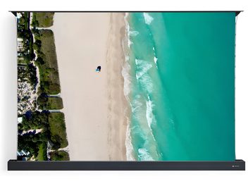 Écran de projection sur pied Projeo Rise HD 100 avec toile affichant une vue aérienne de plage et mer turquoise