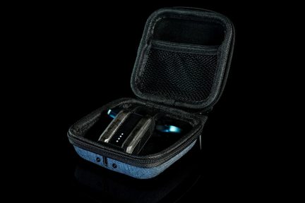 Blå og sort stofbetrukket hårdtui, set i trekvartsprofil, med åbent låg, der afslører et netlomme og en lille sort elektronisk enhed med gennemsigtige sider udstyret med fire LED-indikatorer