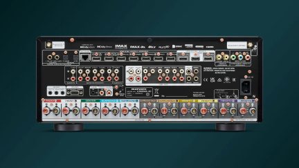Parte trasera de un amplificador AV negro de metal, con múltiples puertos HDMI y RCA, bornes para altavoces, Ethernet y antenas