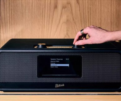 Radio Roberts nera dal design rétro, con display centrale e comandi dorati sulla parte superiore, mano sulla manopola destra