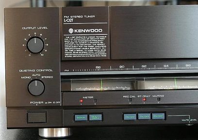 Frontpanel på en Kenwood L-02T stereotuneren med knapper, drejeknapper, digitalt display og stik til hovedtelefoner og mikrofon
