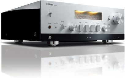 Yamaha R-N2000A silver hi-fi stereo amplifier, front view, silver faceplate with buttons and display, two black speakers