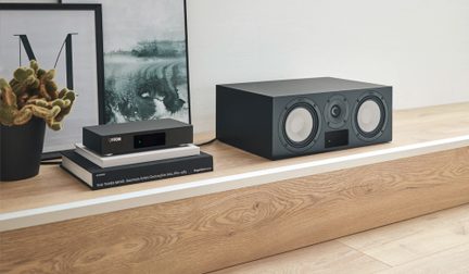 Set audio hi-fi Canton con amplificatore nero compatto e diffusore centrale a tre vie su mobile in legno chiaro