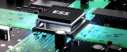 Vedere de aproape a unui circuit imprimat cu un component central negru marcat „ESS”, înconjurat de trasee verzi și alte componente