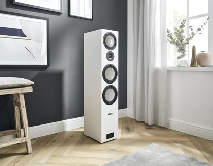 Bílý sloupový hi-fi reproduktor Canton se čtyřmi kulatými měniči, umístěný v moderním, světlém obývacím pokoji