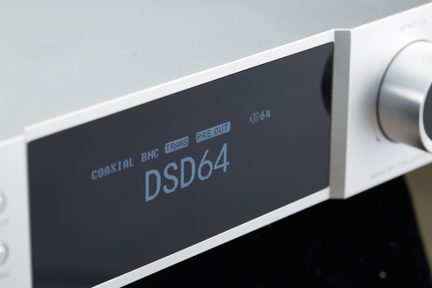 Silver aluminum audio case, three-quarter front view, featuring a black front display with light blue text and a large metal knob on the right side
