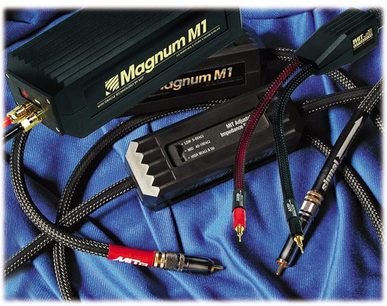 Sorte Magnum M1 RCA-lydkabler med forgyldte stik, på blå plisseret stof, tæt på-billede