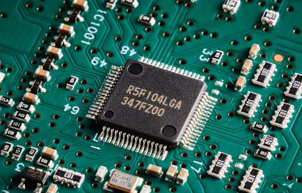 Микроконтролер R5F104LGA, черен, върху зелена електронна платка с SMD компоненти, показани в детайлен близък план