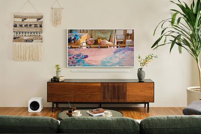 Samsung F-TQ55LS03D-BF højdefinitions-tv monteret på væggen, kunstbillede vist, træmøbel, grøn plante, grøn sofa