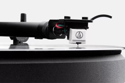 Balta Audio-Technica skaņas noņēmēja galviņa uz melna tonarma, adata uz vinila plates tuvplānā
