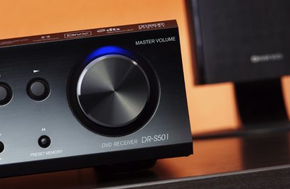 Frontvue af Onkyo LS-V501 hjemmebiografsystem, volumeknap, DVD-modtager S501, blå belysning omkring knappen