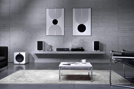 Moderne woonkamer met wit en zwart hi-fi-systeem, platenspeler, subwoofer en luidsprekers op wandplank