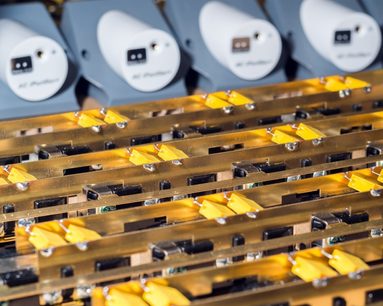 Graue elektrische Mehrfachsteckdosen mit orangefarbenen Leuchtanzeigen, Nahaufnahme von oben auf mehrere Reihen