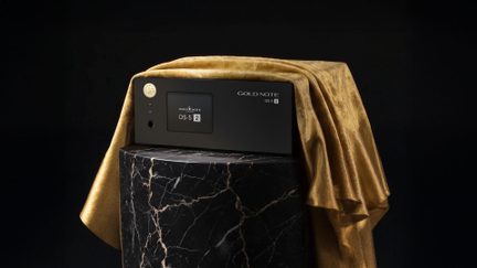 Lettore di rete Gold Note DS-5 2 nero con schermo frontale, posato su una base nera venata sotto un drappeggio dorato