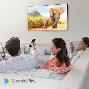Fladskærms-tv, der viser et billede af elefanter på savannen, betragtet af en mand og en kvinde, der sidder på en lysegrå sofa