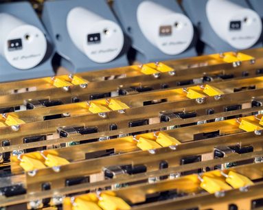 Graue elektrische Mehrfachsteckdosen mit orangefarbenen Leuchtanzeigen, Nahaufnahme von oben auf mehrere Reihen
