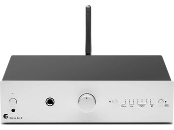Amplificador hi-fi integrado estéreo Pro-Ject Stereo Box E plateado, vista frontal, carcasa rectangular, botón central circular, conectores y antena vertical.