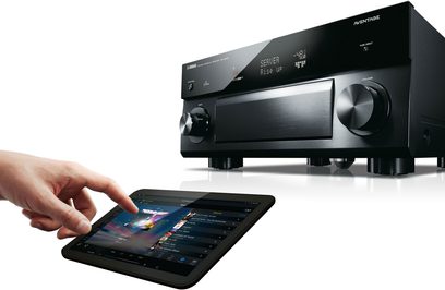 Yamaha RX-A3050 sort hjemmebiografsforstærker med sort front, LCD-skærm, knapper og drejeknapper. Hånd rører ved tablet-skærm
